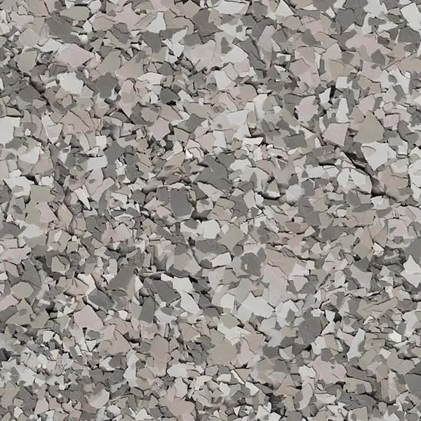 A textured surface featuring small, irregularly shaped gray and white flakes, creating a camouflaged and abstract appearance without identifiable landmarks or objects.